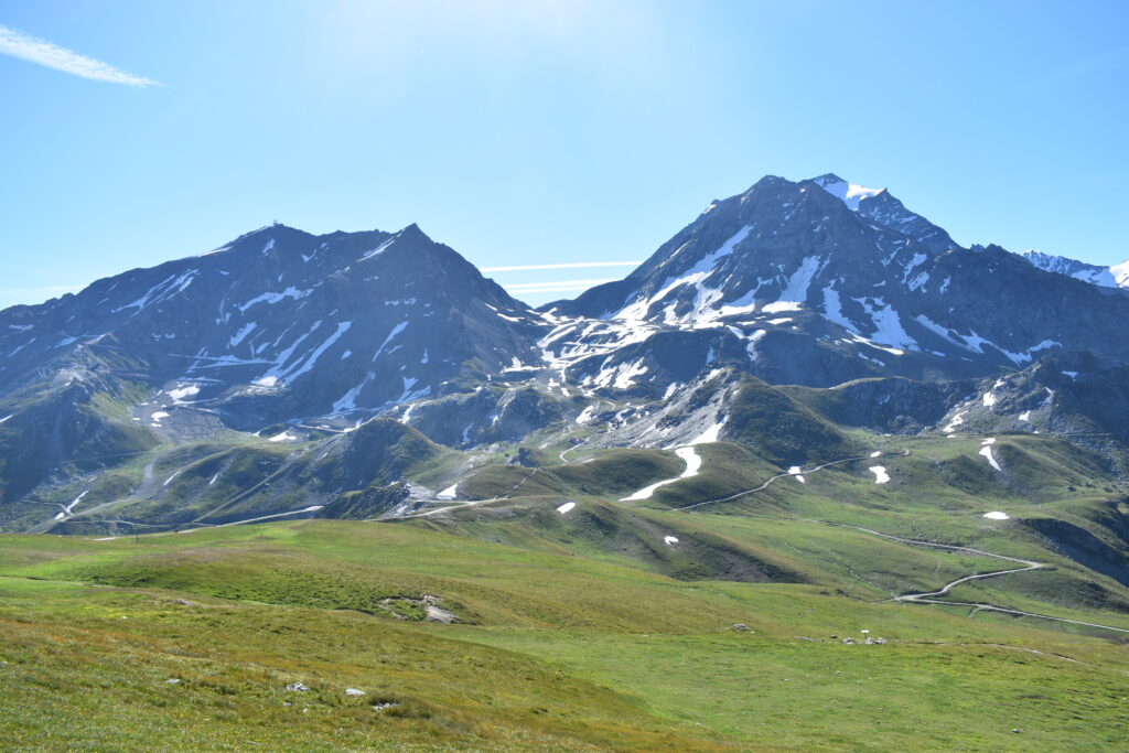 Alpages verdoyants et sommets rocheux du domaine en été. L'Aiguille Rouge et le Grand Col