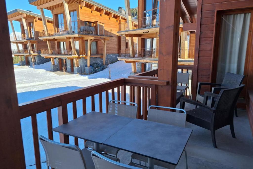 Balcon enneigé meublé d'une table et de chaises, face aux pistes