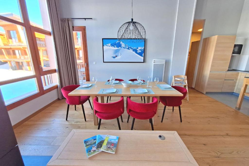 Coin repas et chaises rouges devant la baie vitrée